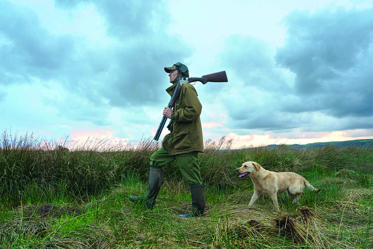 man with shotgun and labrador